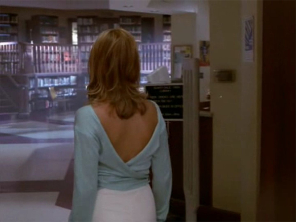 Buffy stands in an empty library, facing away from the camera.
