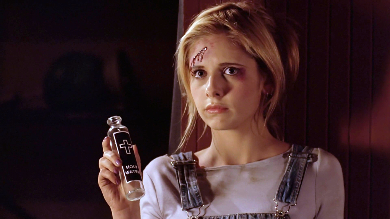 Buffy holds a bottle of holy water as she looks defiantly at Kralik.